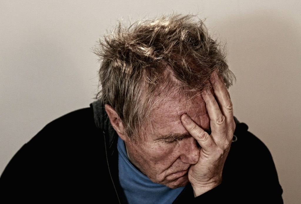 Homme qui tient sa tête dans les mains et qui à l'air triste et seul 