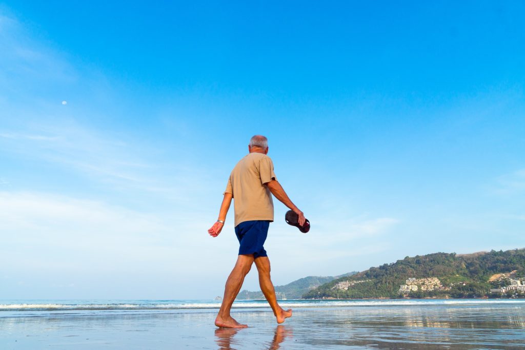 Homme âgé seul qui se balade sur la plage