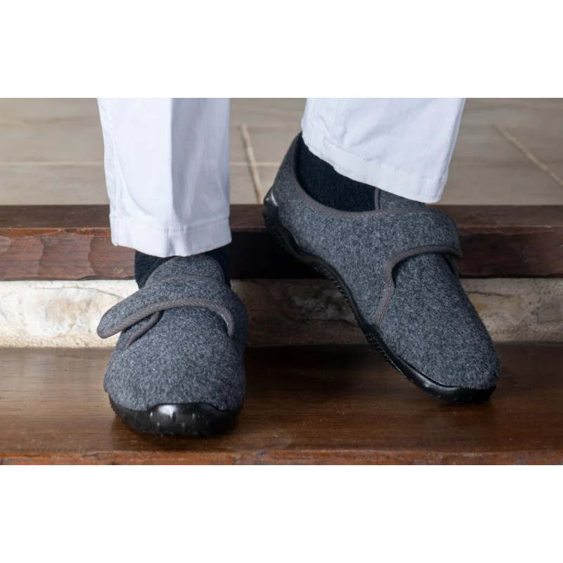 Homme portant des chaussons Airflex gris à scratch sur des marches intérieures