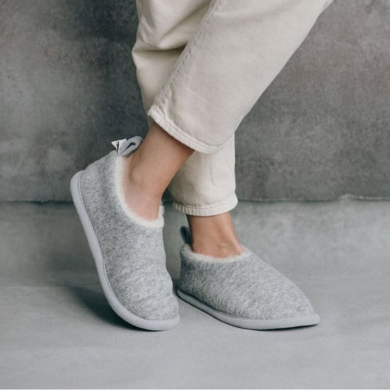 Personne portant des chaussons gris en laine mérinos avec doublure douce